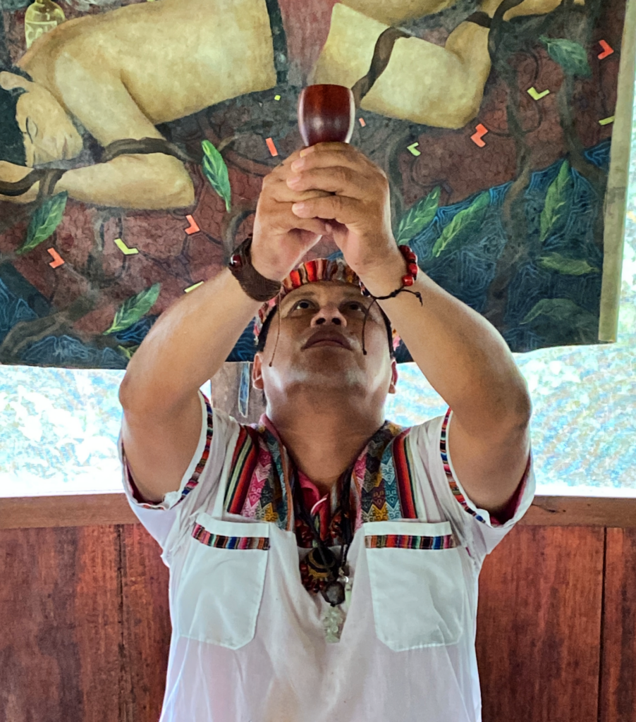 A shaman holds a cup of ayahuasca toward the sky at an ayahuasca retreat